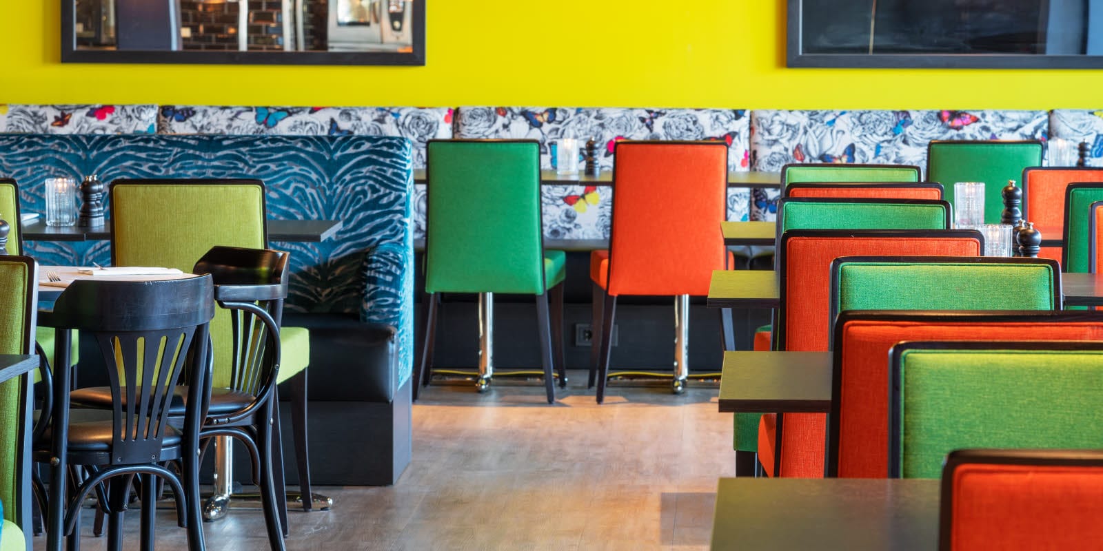 Restaurant med sitteplasser med gul vegg, og fargerike møbler på Thon Hotel Triaden i Lørenskog