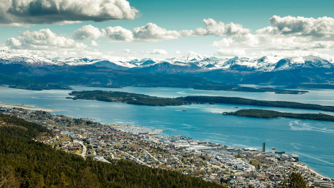 Vakker utsikt over Moldefjorden. I forgrunnen ligger byens sentrum hvor vårt hotell i Molde ligger. I bakgrunnen ligger snøbelagte fjell.
