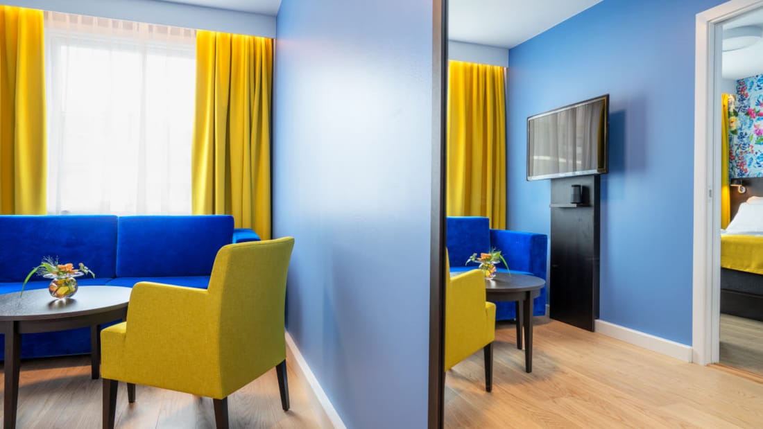 Sittegruppe med blå soffa og gule stoler i suite på Thon Hotel Moldefjord
