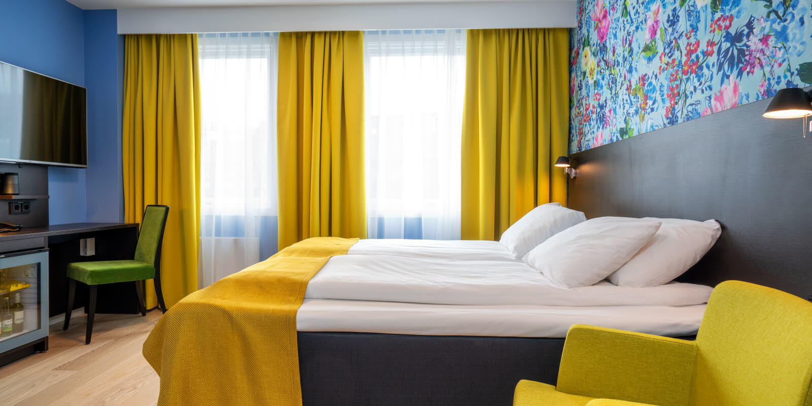 Stol, dobbeltseng, skrivebord og blomstrete tapet på Thon Hotel Moldefjord