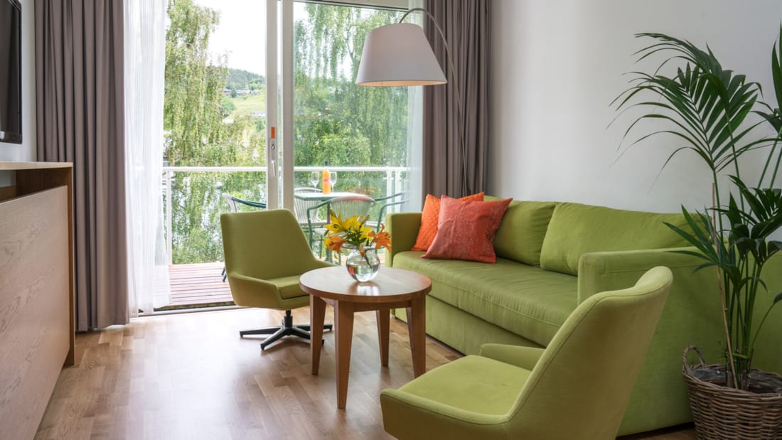 Blomster på bord i stua med sofa og to stoler på Thon Hotel Sandven i Nordheimsund