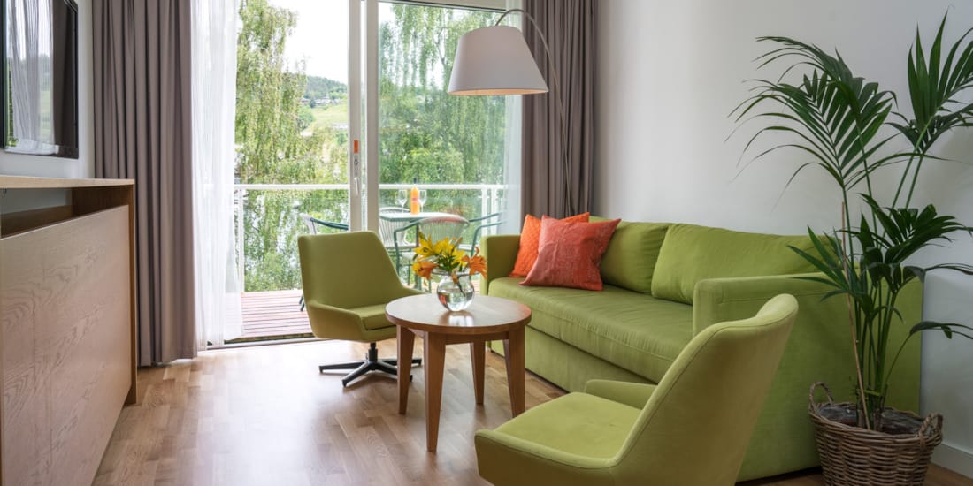 Blomster på bord i stua med sofa og to stoler på Thon Hotel Sandven i Nordheimsund