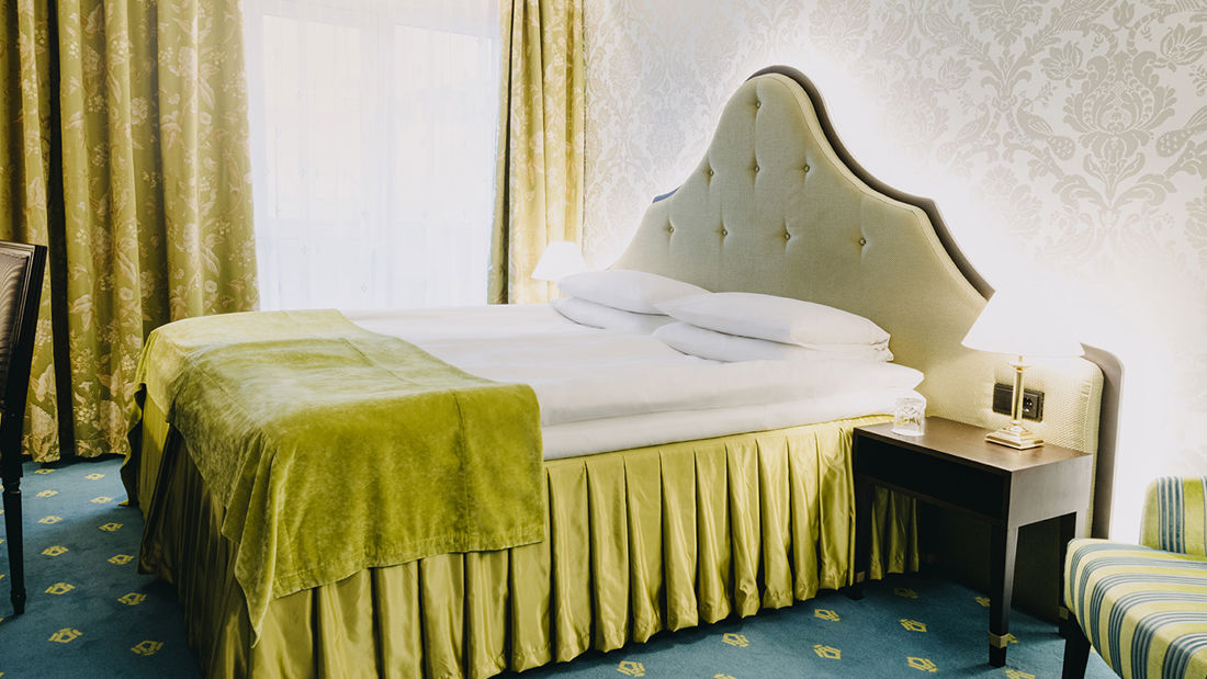 Seng med nattbord og stol i standardrom på Hotel Bristol i Oslo