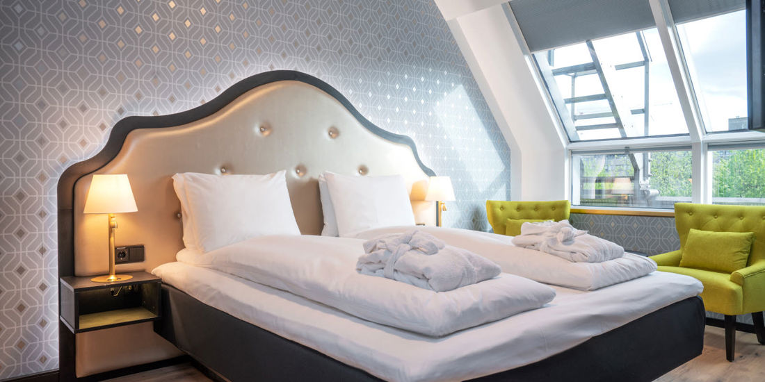 Seng, spisebord og sittegruppe i suite på Thon Hotel Cecil i Oslo sentrum