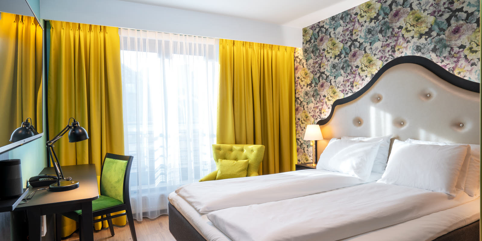 Superiorrom hos Thon Hotel Nordlys. Dobbeltseng med bilde av nordlys bak sengegavl, skrivebord og utsikt over sjøen.