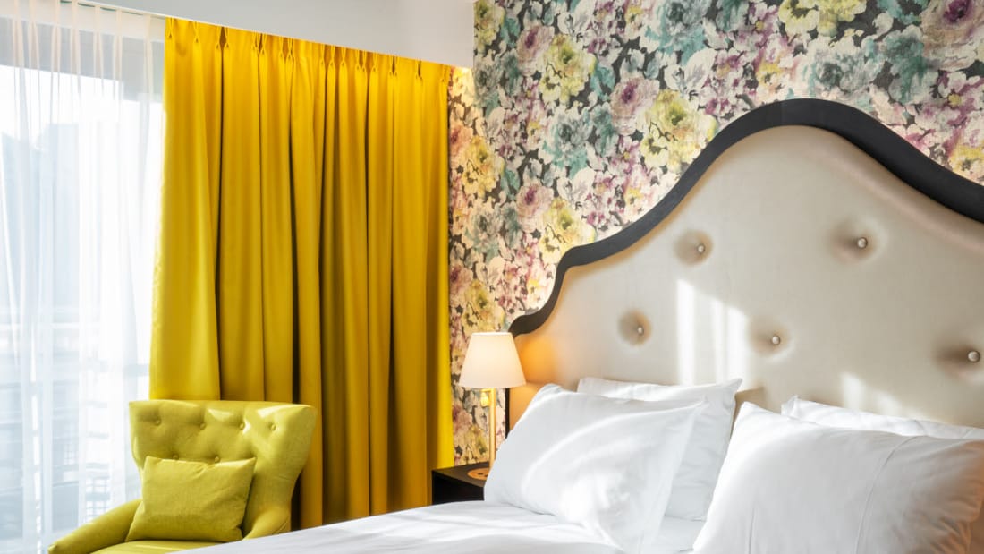 Blomstret tapet og dobbeltseng i dobbeltrom, gule gardiner på Thon Hotel Cecil i Oslo sentrum