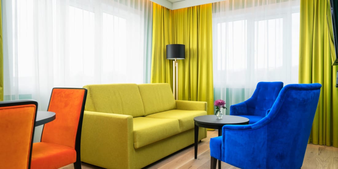 Gul sofa med lenestoler i forskjellige farger på suite Thon Hotel Europa i Oslo sentrum rett ved Slottsparken
