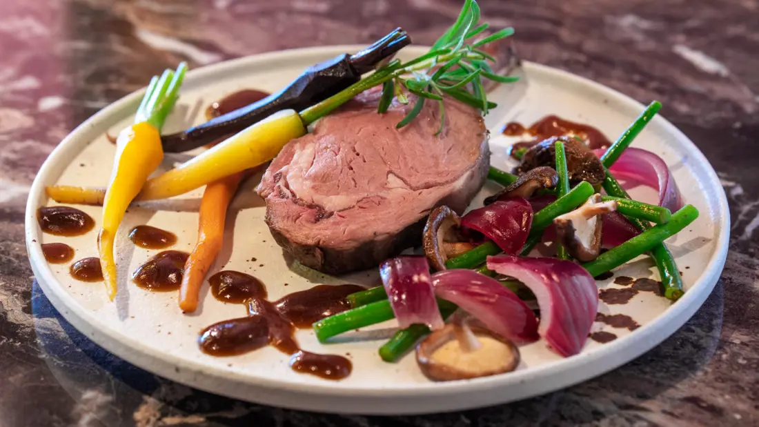 Mørt kjøtt omkranset av grønnsaker på et fat