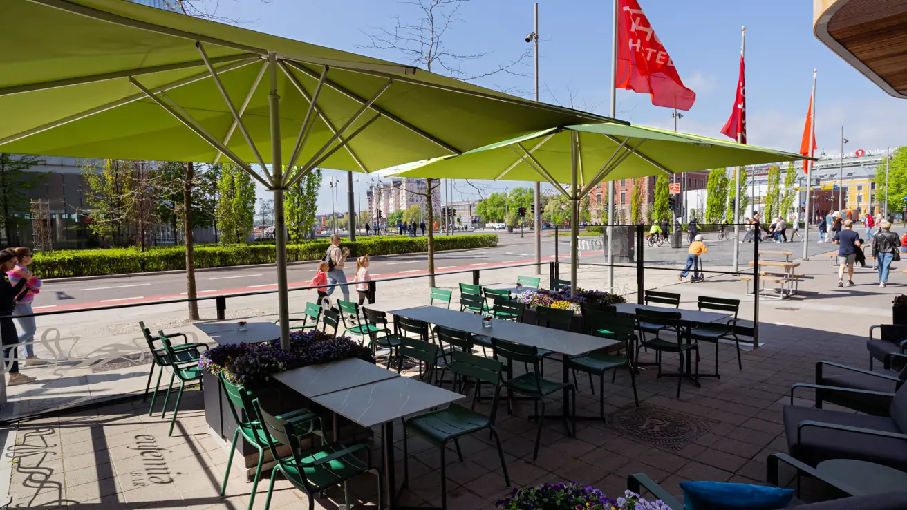 Eufemia bar sin uteplass med grønne parasoller, bord og stoler langs fortau i Bjørvika.