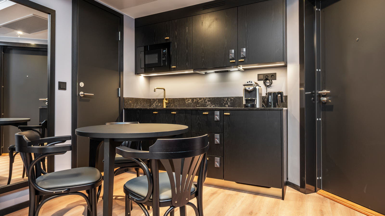 Stort hotellrom med rund spisebord og spisestoler og et lite kj&#xF8;kken.