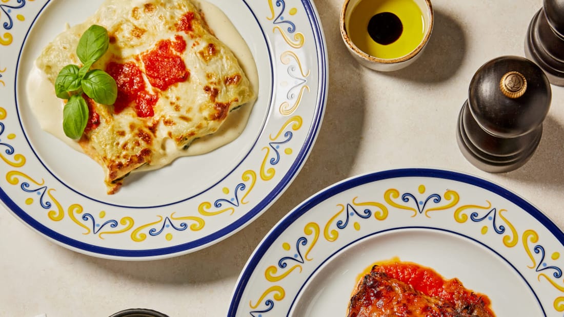 Utsnitt av to italienske retter dandert på hvite tallerkener med gul og blå kant. 
