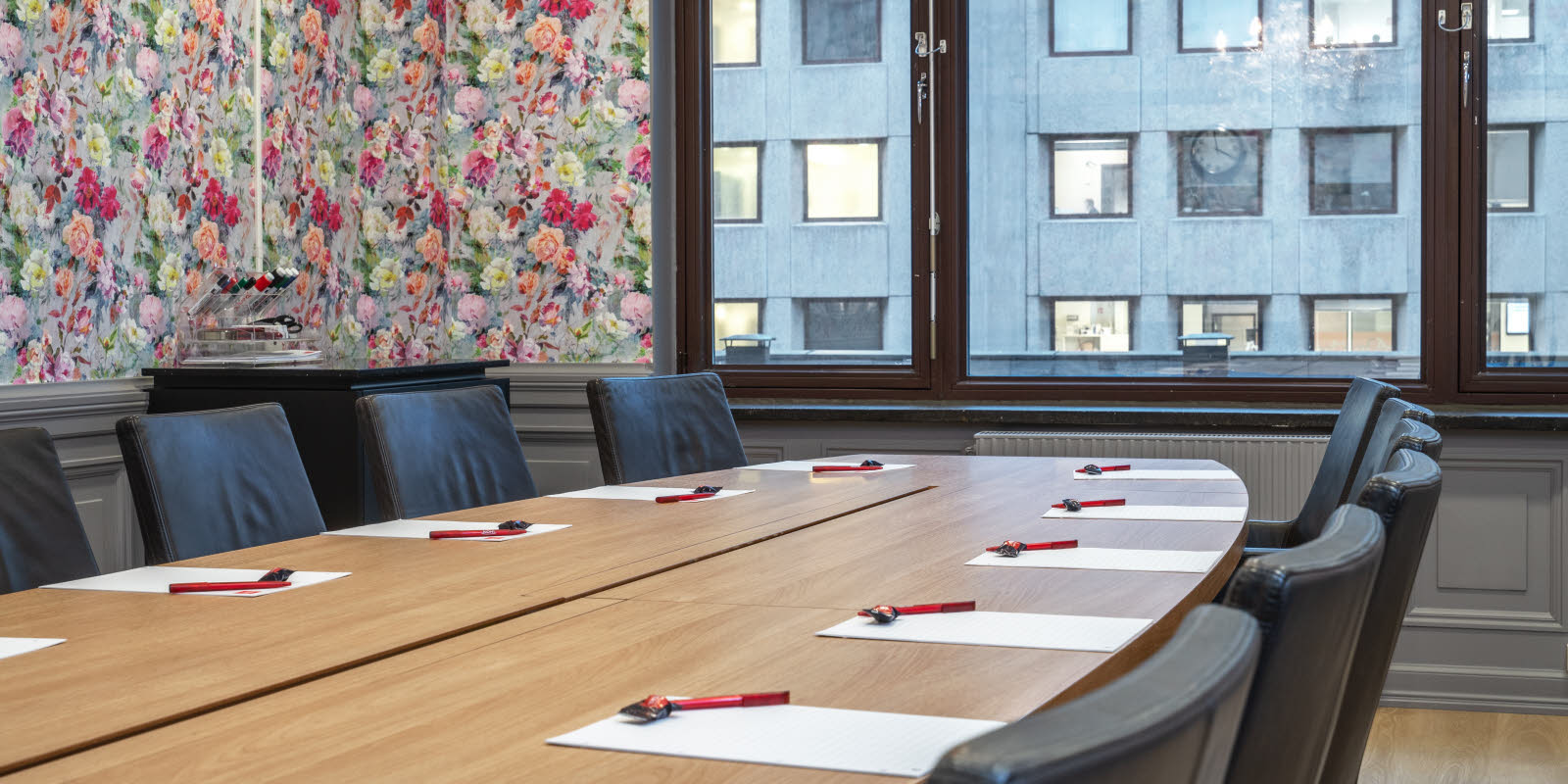 konferanserom stella, 13 plasser rundt ovalt bord, vindu, klokke og malerier på vegg, lysekrone i tak