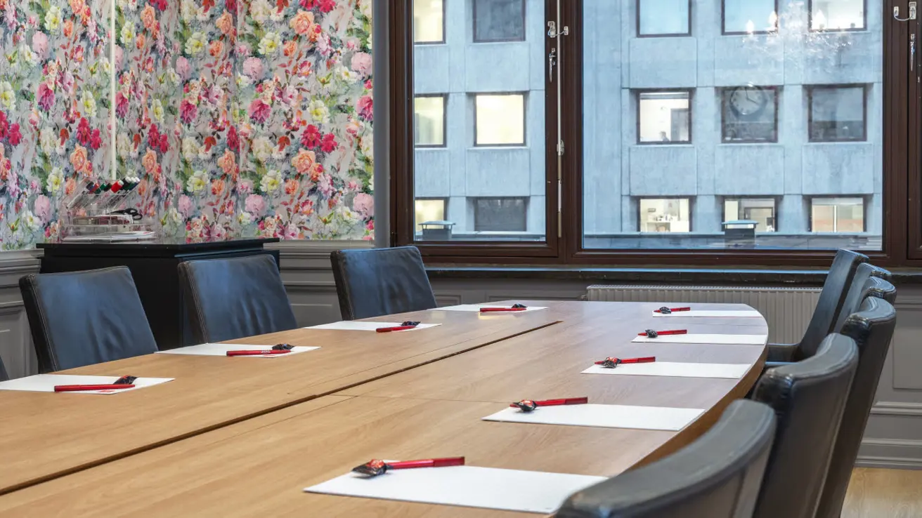 konferanserom stella, 13 plasser rundt ovalt bord, vindu, klokke og malerier på vegg, lysekrone i tak