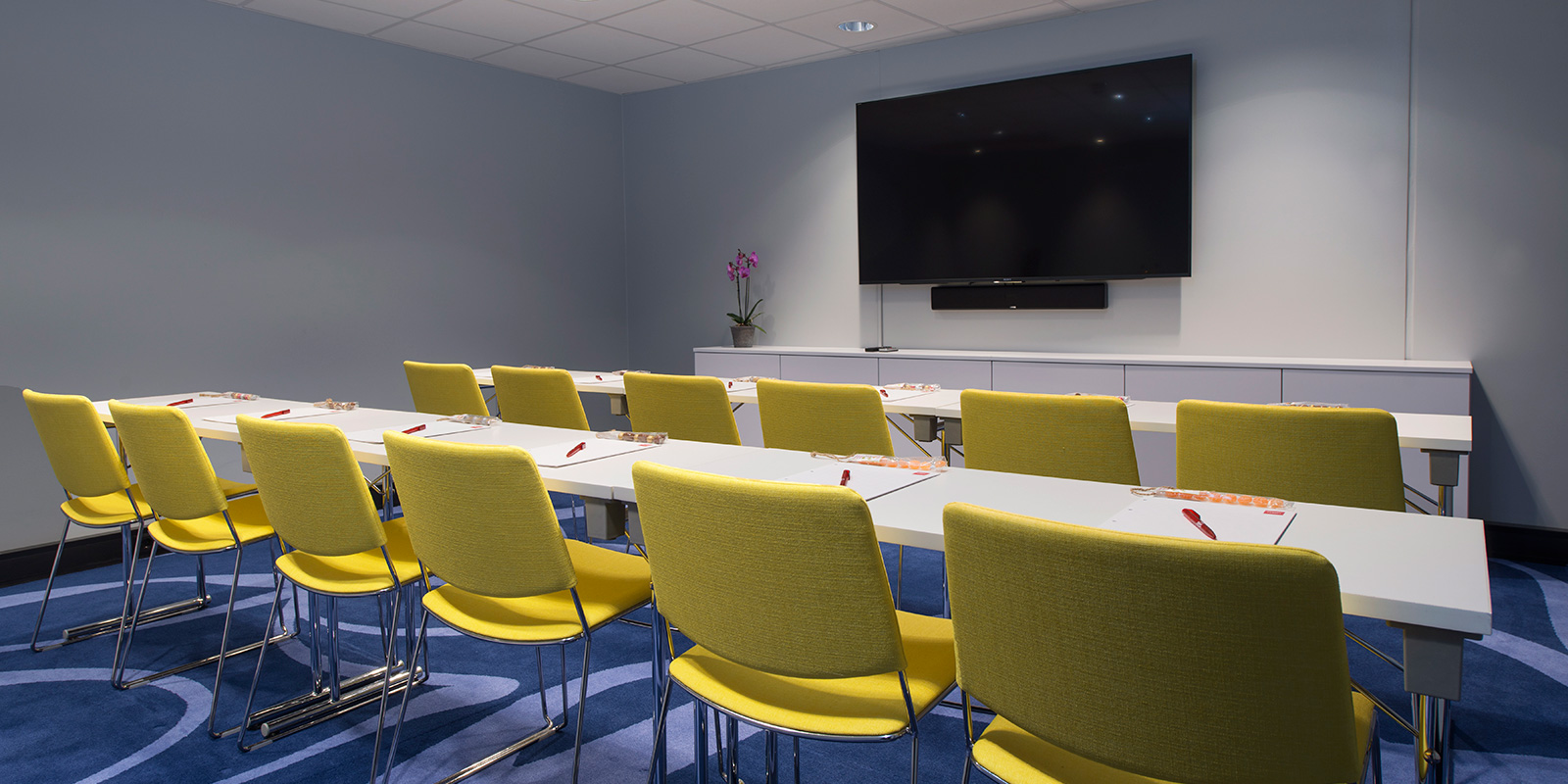 konferanse møterom 3 langbord, 12 plasser, notatblokker, vegghengt presentasjonsskjerm i forkant