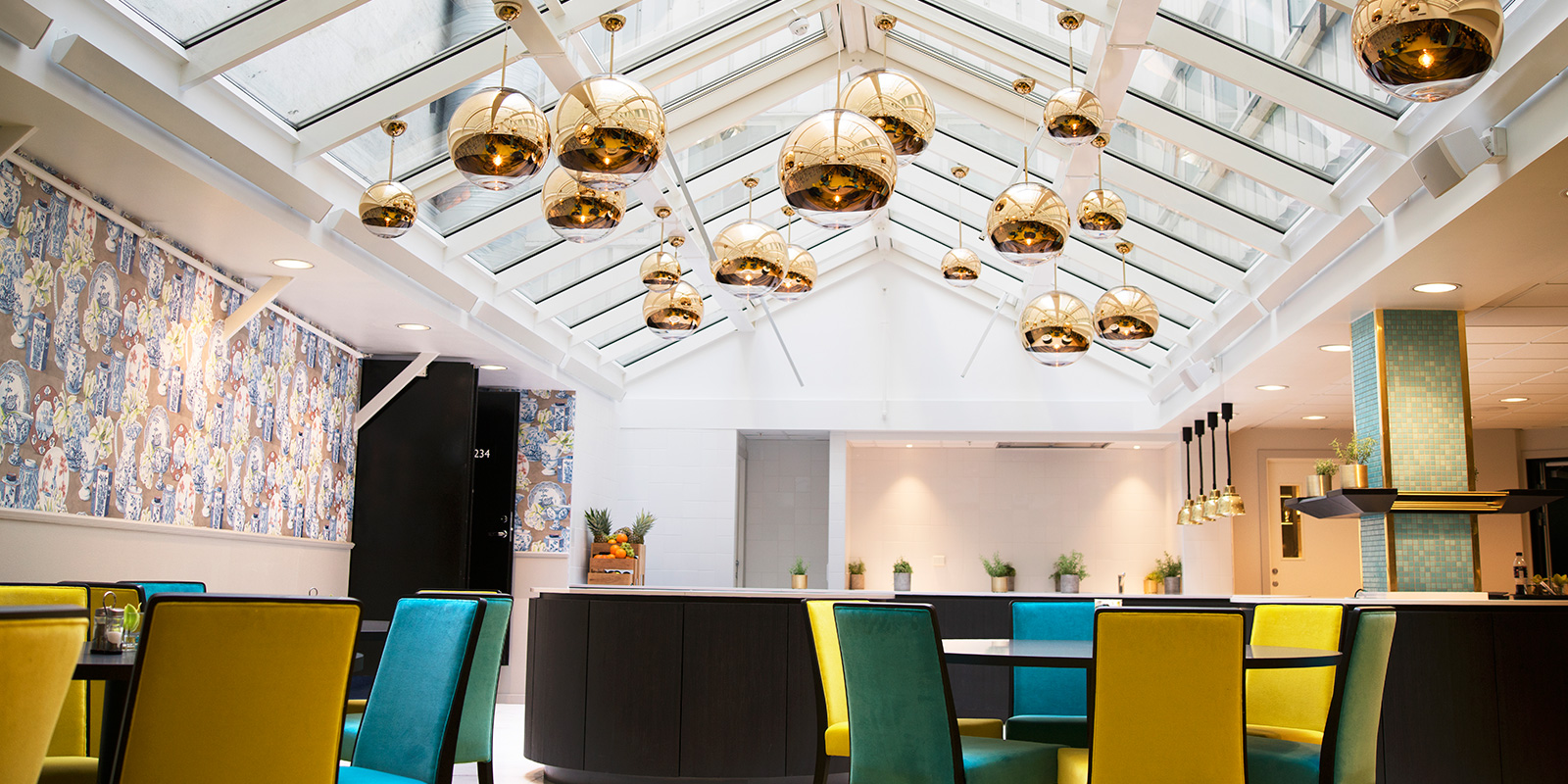 frokostsal bord og stoler, lamper henger ned fra glasstak