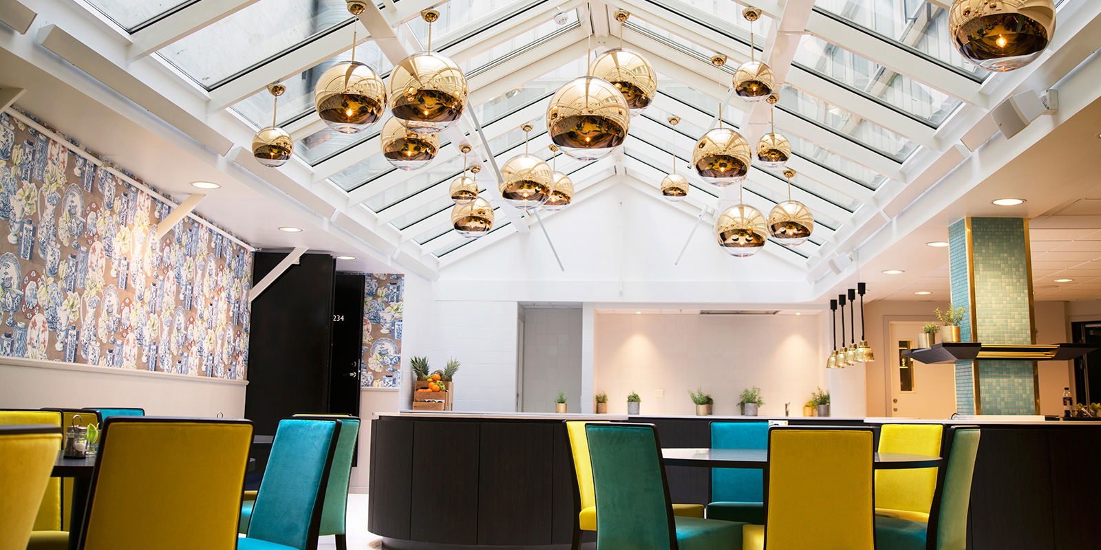 frokostsal bord og stoler, lamper henger ned fra glasstak