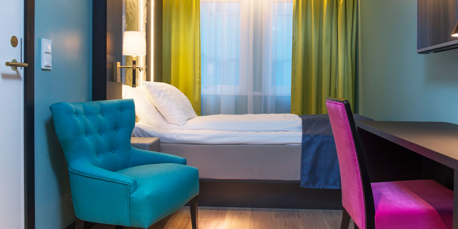 small single room enkeltseng, skrivebord, en lenestol, vindu med lystette gardiner i bakkant