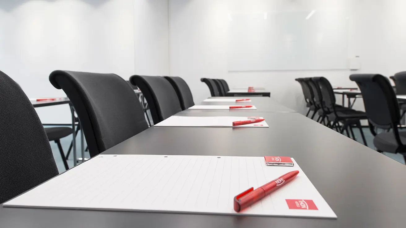 detaljbilde av konferansestoler og bor på rekke med notatblokker og penn