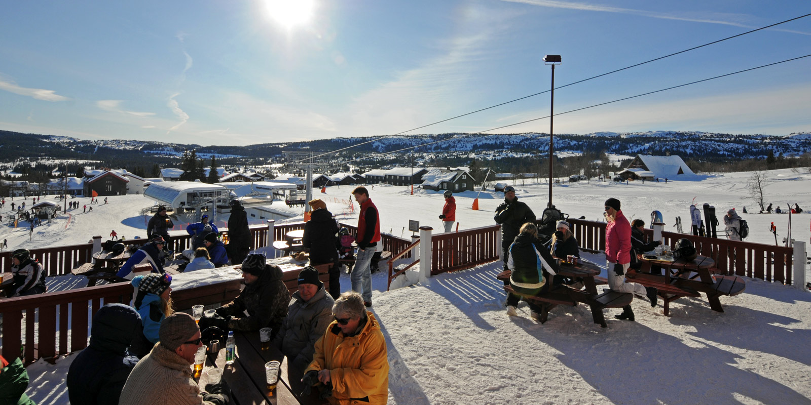 Uteplass Nystua mange mennesker i vinterklær stående på et uteområde med solskinn