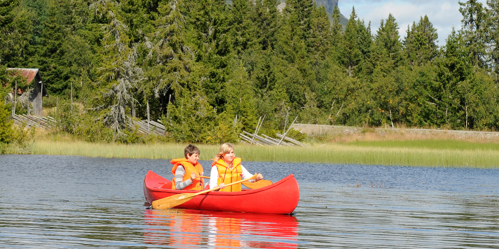 To mennesker som padler en rød kano i solskinn