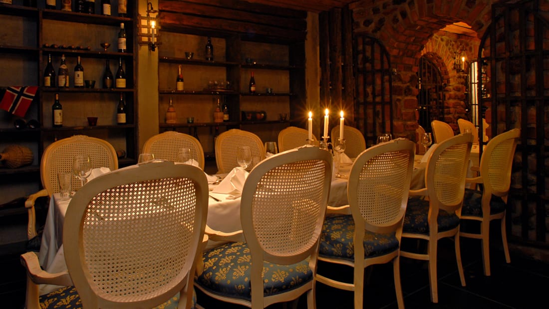 Dekket bord vinbodega med tente lys og dekket hvitt bord.