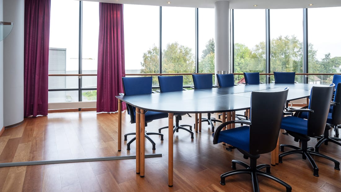 Stort møtebord med tilhørende stoler på lyst og luftig møterom på Stavanger Forum Hotel