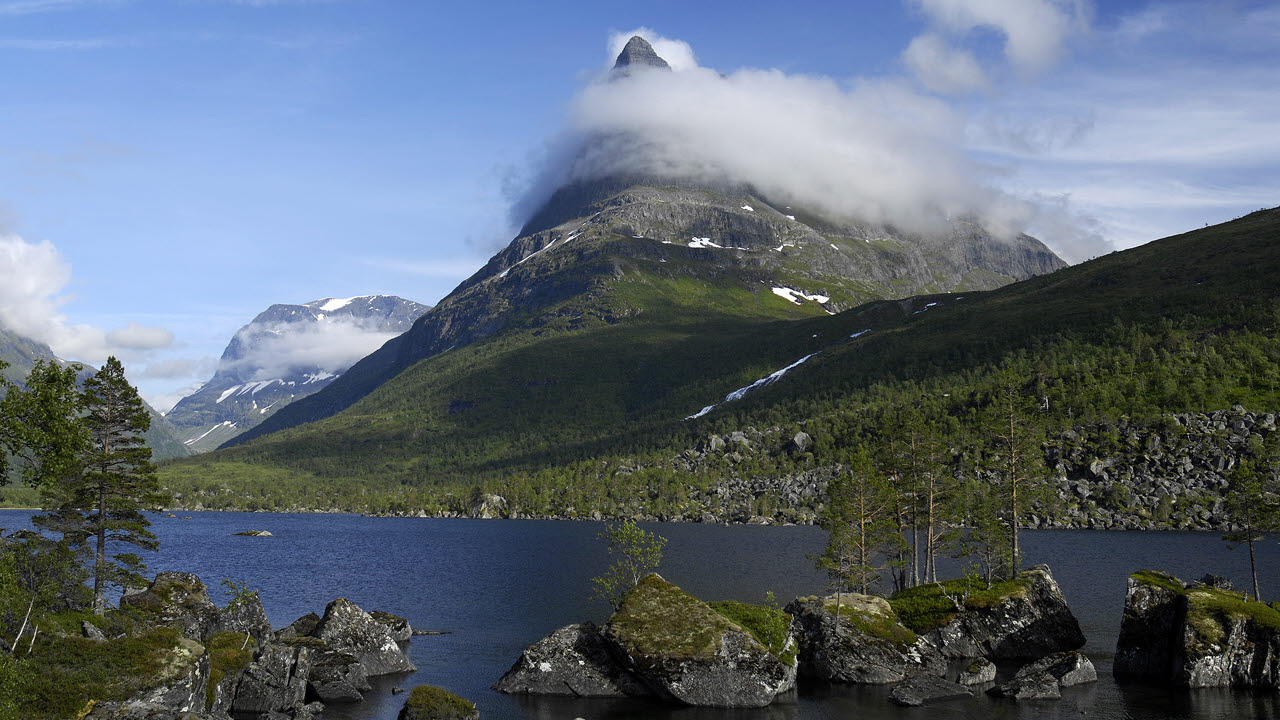 Et fjellandskap med en innsjø omgitt av trær.