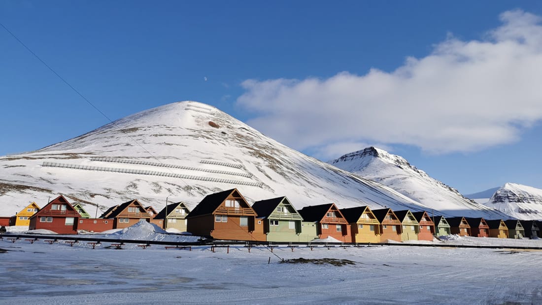 Fargerike leiligheter ved foten av et snødekt fjell.