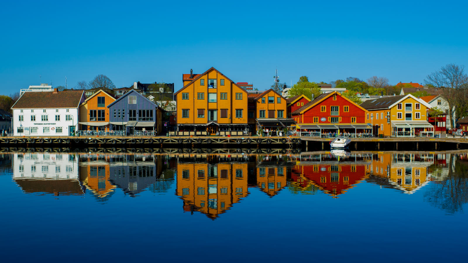 Fargerike bygninger speiler seg i vannet.