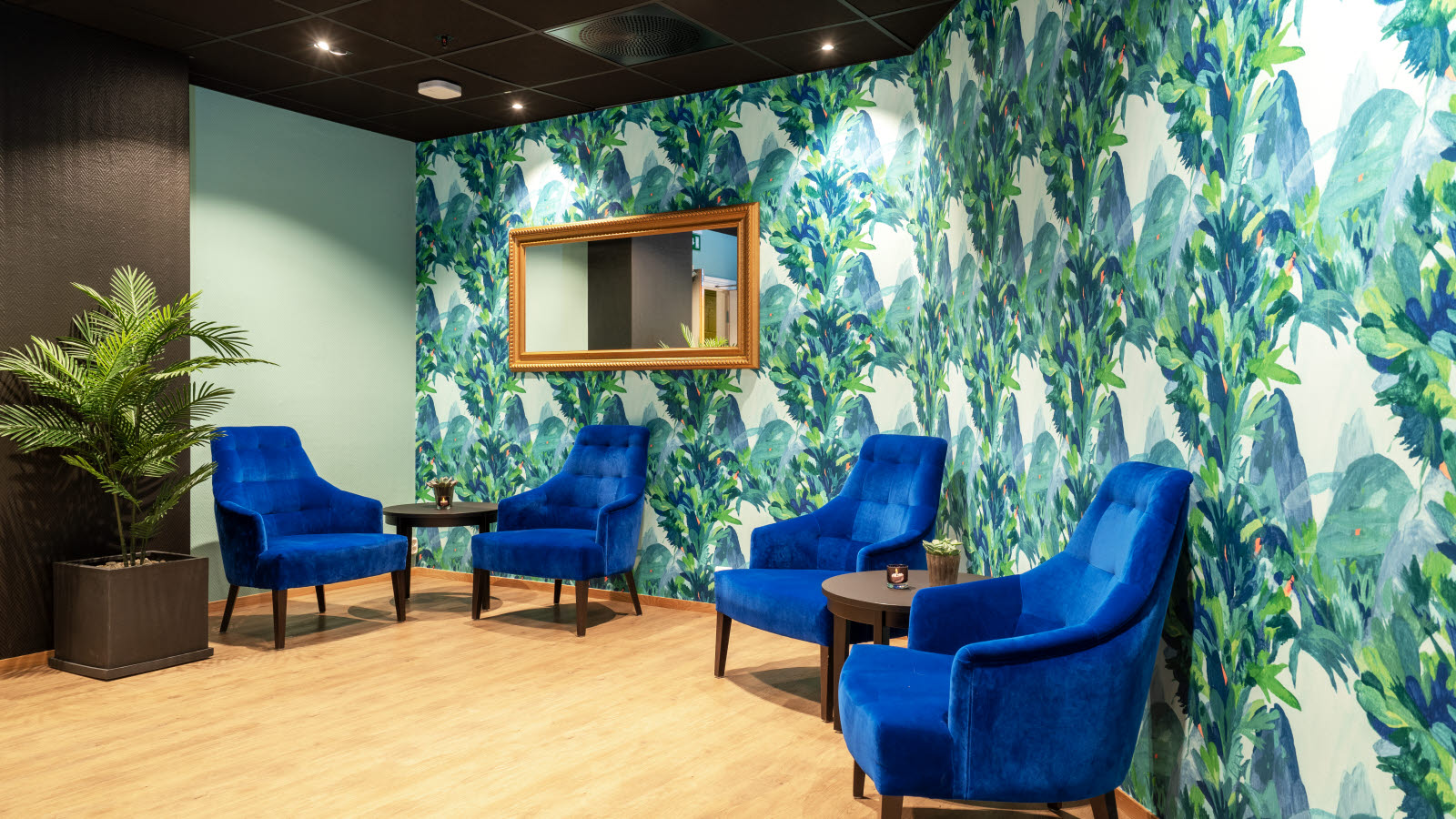 Lobby med blå stoler og grønn tapet.