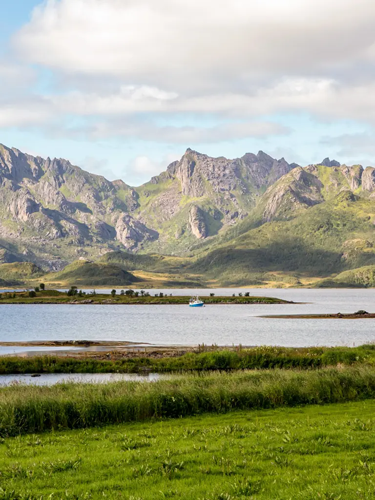 Landskap i Sortland i Vesterålen med sjø, og høye fjell i bakgrunnen.