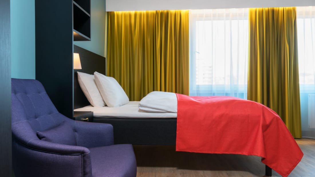 Dobbeltseng og blå lenestol på 1 roms leilighet på Thon Hotel Linne Apartments