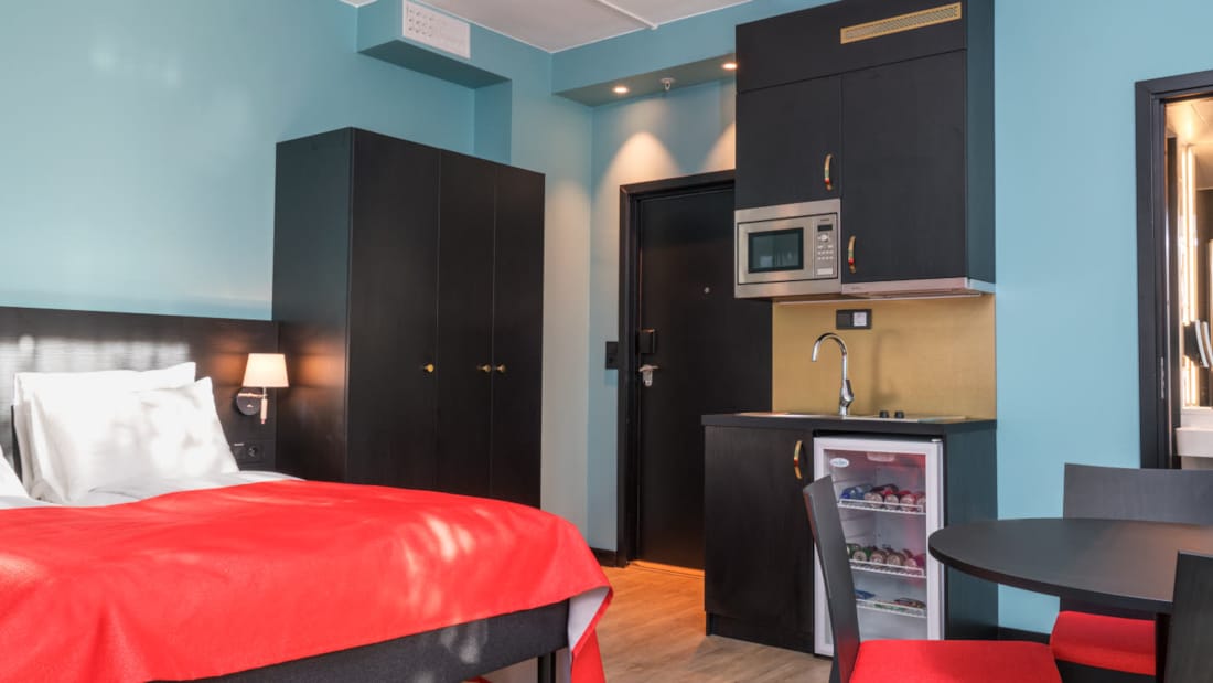 Dobbeltseng, skap, minikjøkken og kjøkkenbord på 2 roms leilighet på Thon Hotel Linne Apartments 