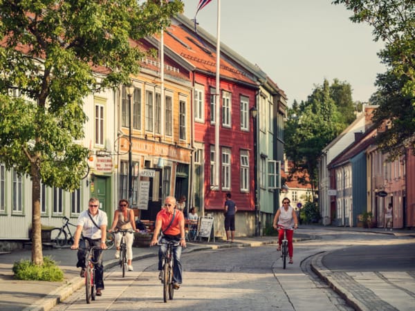Mennesker sykler nedover en gate i en by.