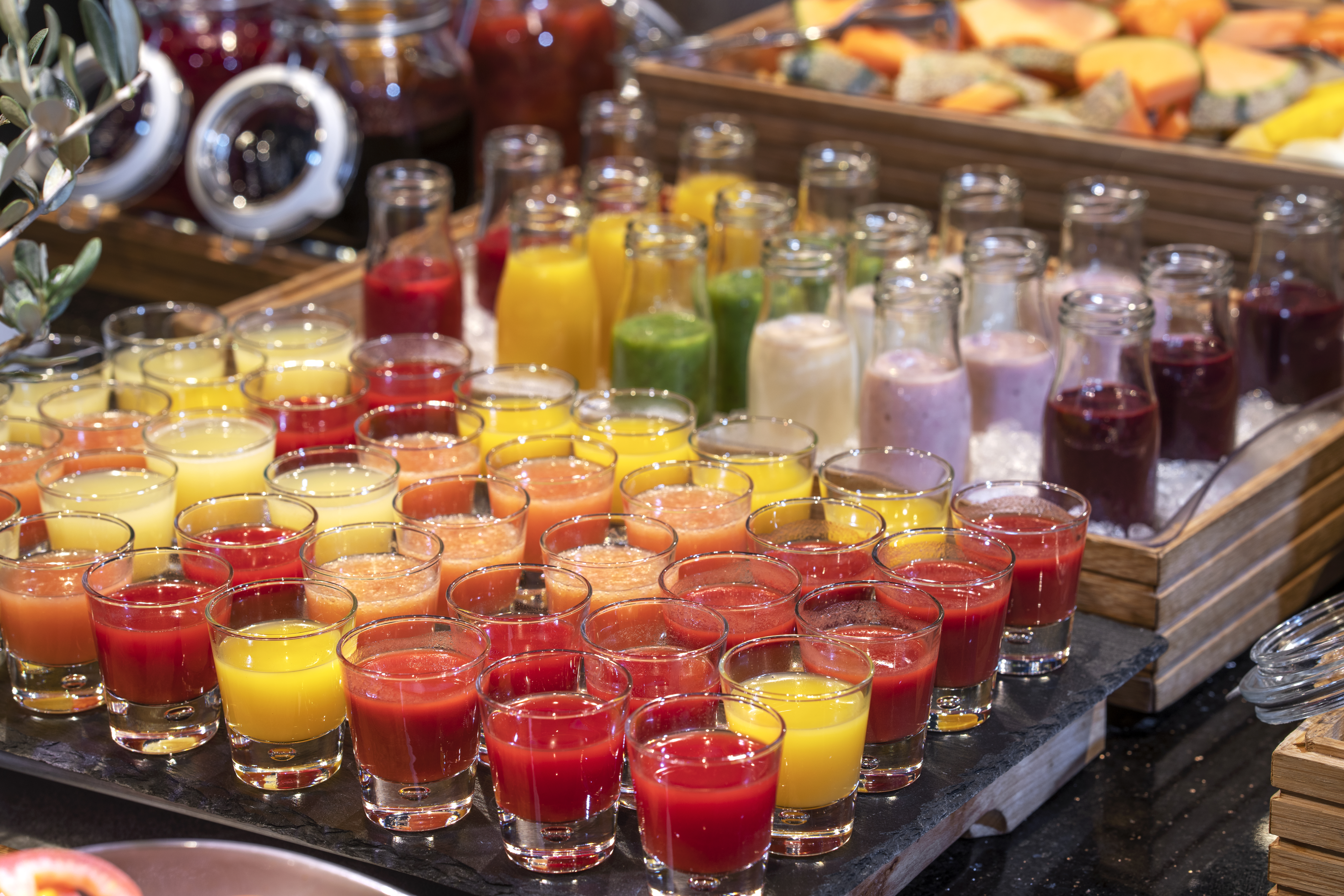 Små glass med fargerik smoothie, stelt på rekker nedover