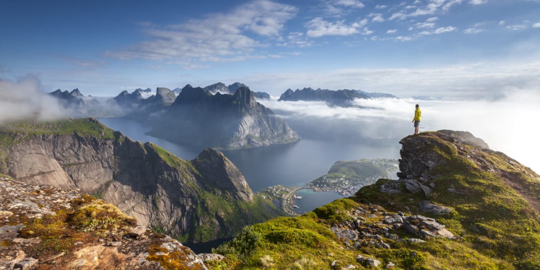 Person som står på toppen av et fjell og ser utover Lofoten