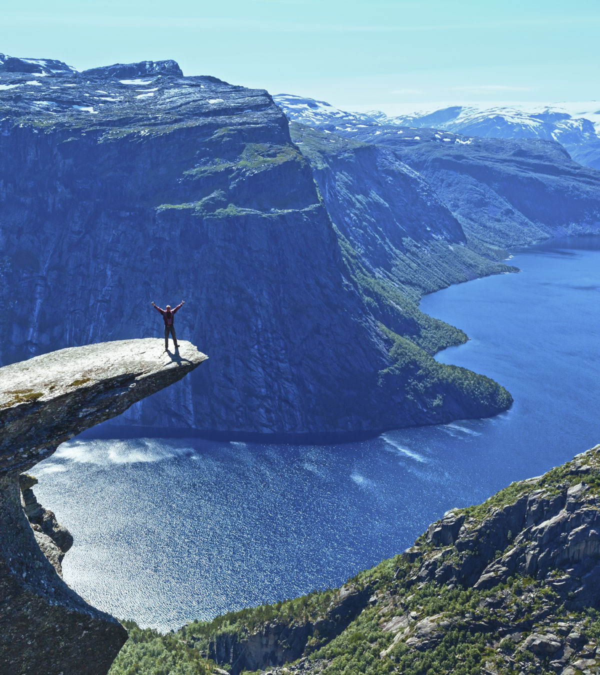 Menneske på Trolltunga foran fjord under blå himmel