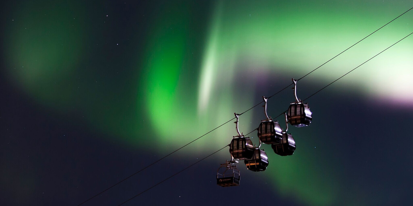 Nordlys som lyser opp himmelen over taubanen