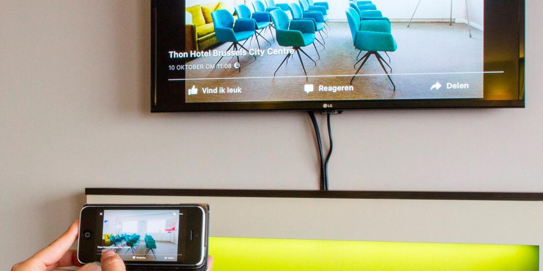 En som styrer TV'en med sin smarttelefon