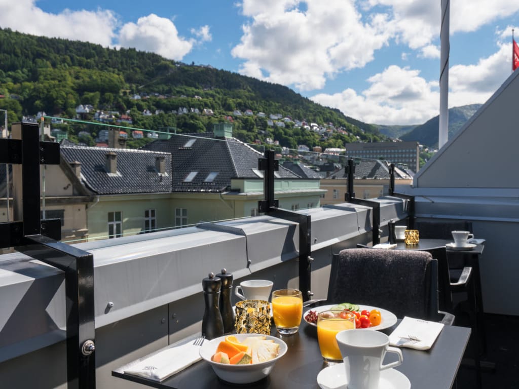  Hotellbalkong med utsikt over fjellene i Bergen, med frokosttallerken på bordet
