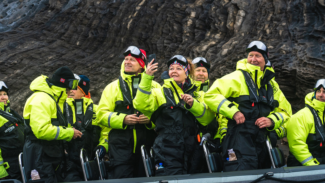 En gruppe mennesker i gule jakker på en Rib-båt.