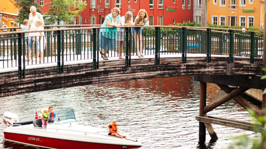 Fiskebryggen i Kristiansand med familie som står på bro og ser ned på båt som passerer