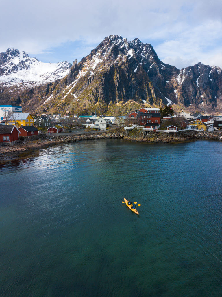 To RIB-er på vei ut mot havet fra havna. I bakgrunnen ses Thon Hotel Lofoten, Svolvær sentrum og snødekte fjell.