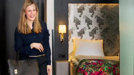 Smilende kvinne som står ved siden av en hotellseng på Thon Hotel Terminus