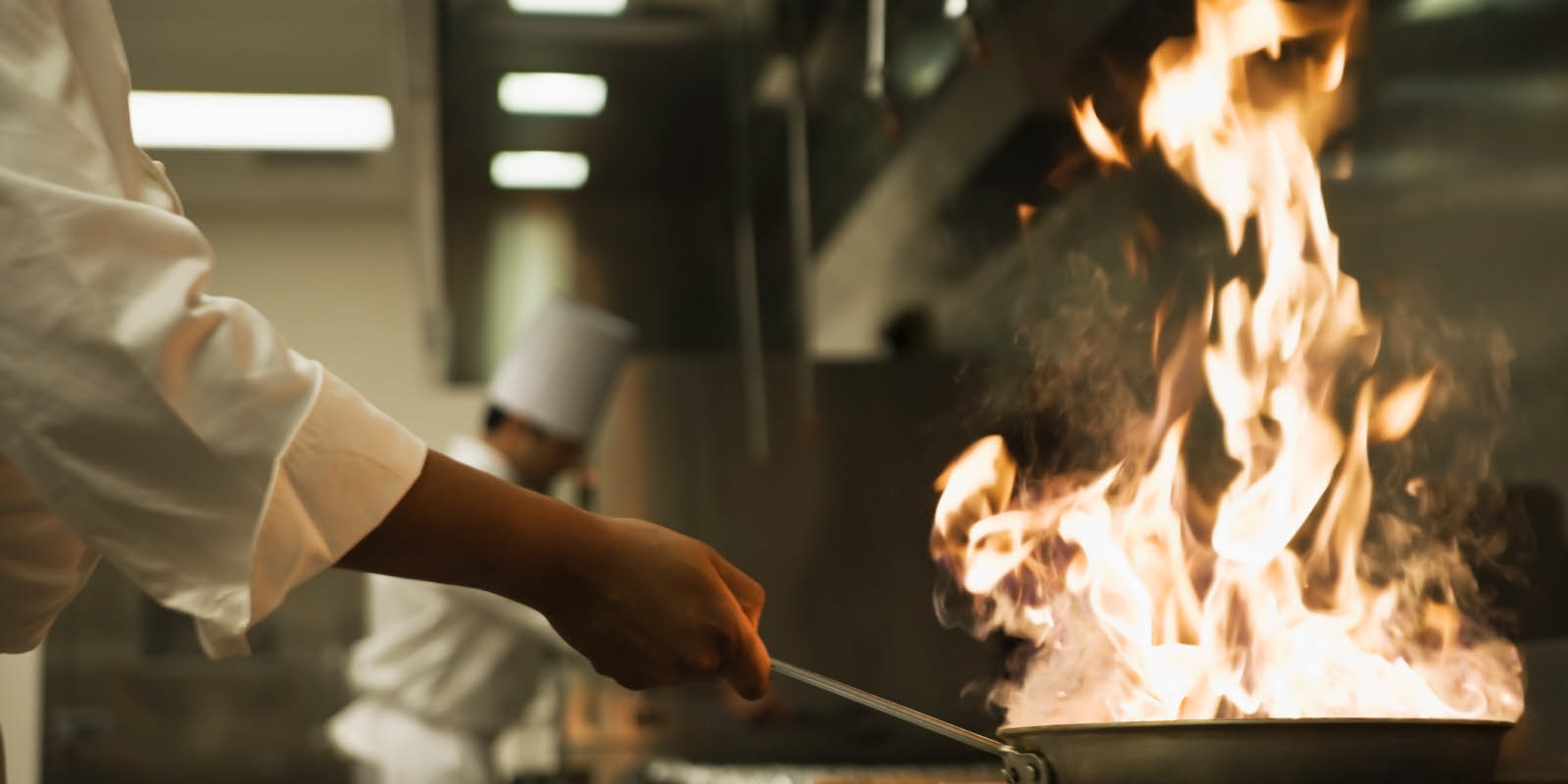 Kokk steker middag i stekepanne med flambering