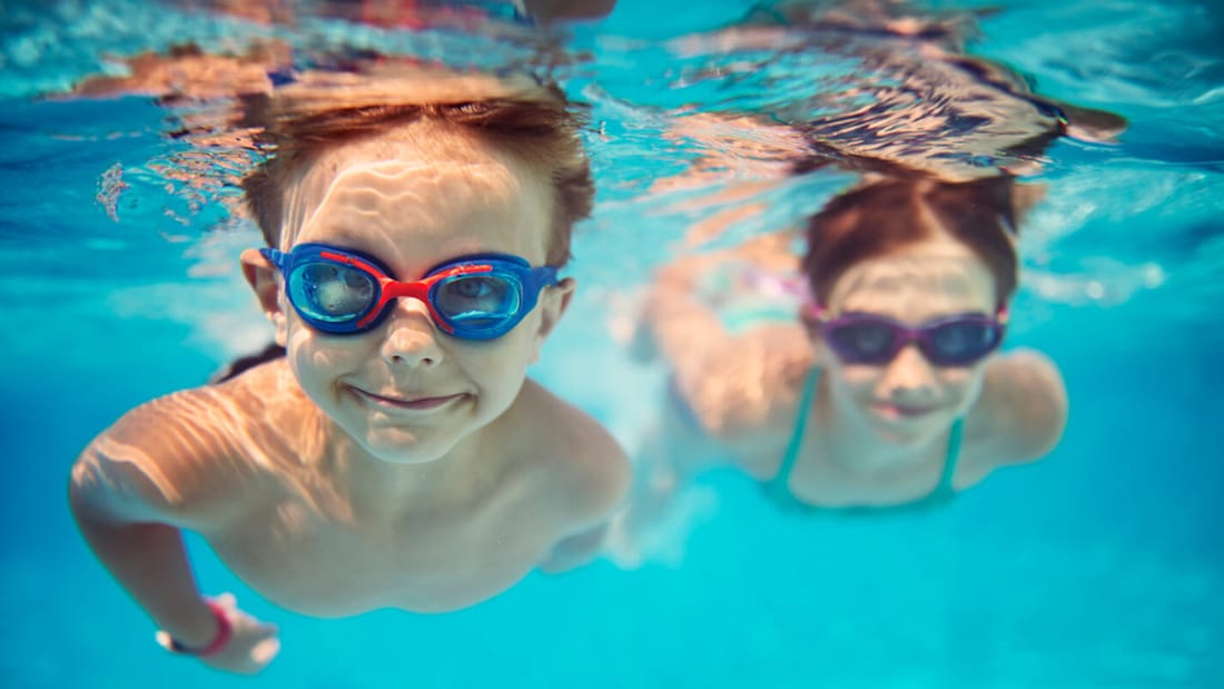 To gutter som svømmer under vann med dykkebriller