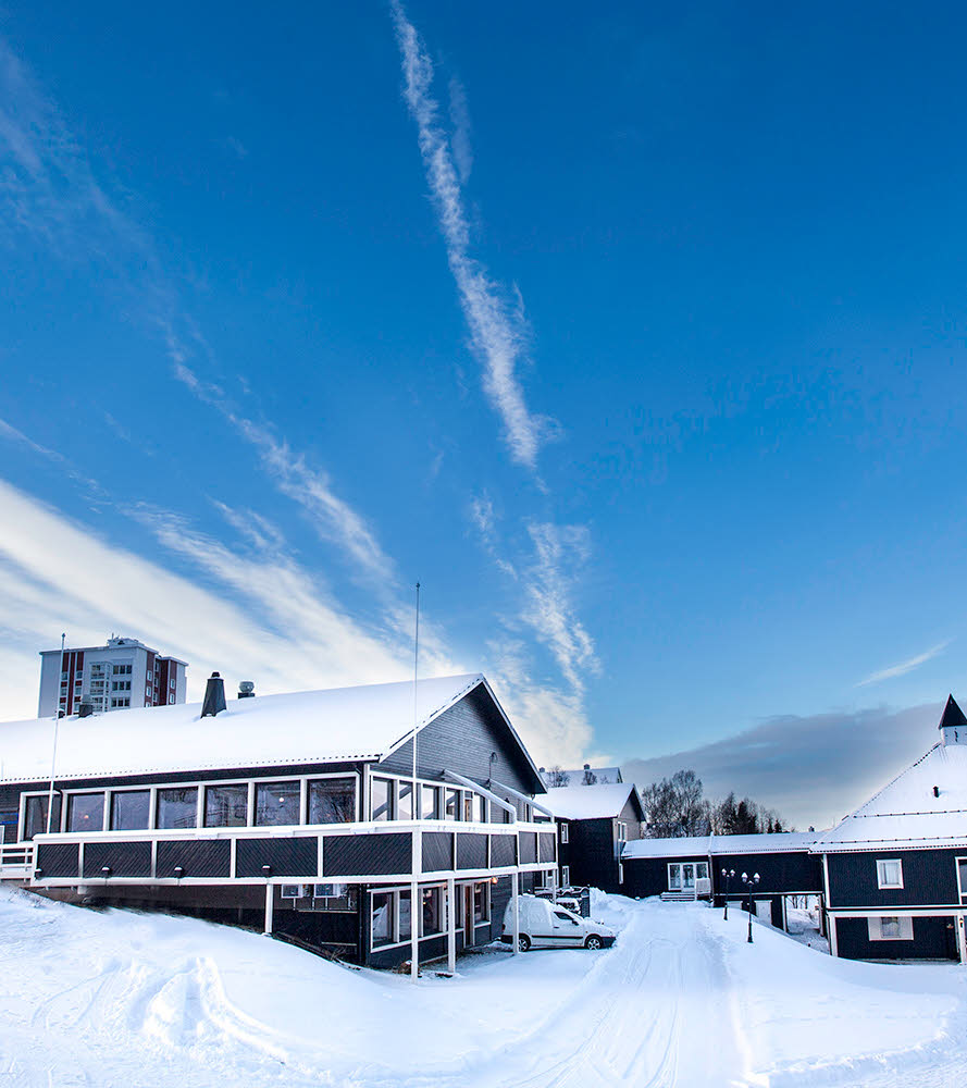 Mørk bygning med snø på bakken.