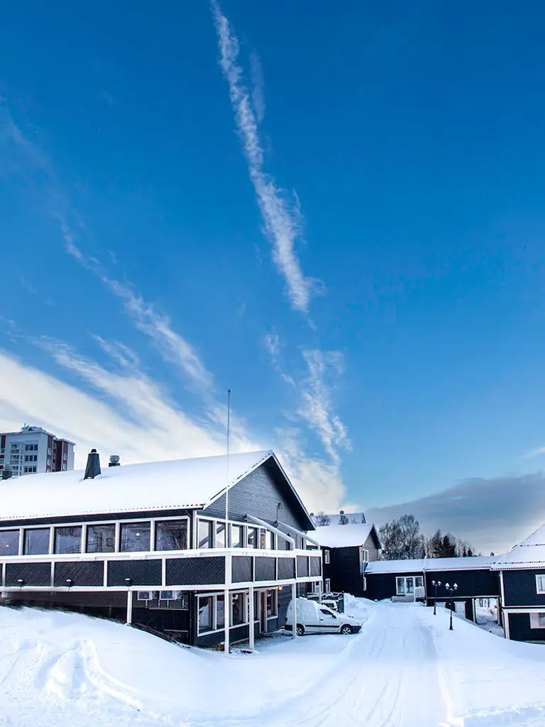 Mørk bygning med snø på bakken.