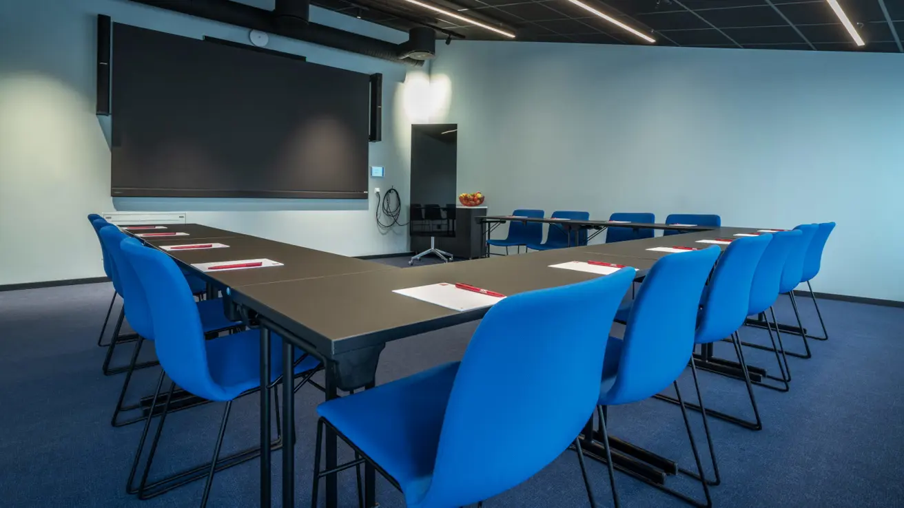 Møterom Røst med blå stoler og tv skjerm